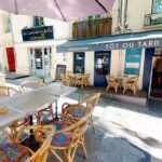 Terrasse de café-restaurant rénovée à Montpellier, façade claire et mobilier en rotin