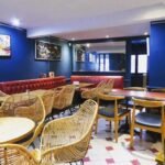 Salle de restaurant repeinte à Montpellier : murs bleus, banquettes rouges et mobilier en rotin